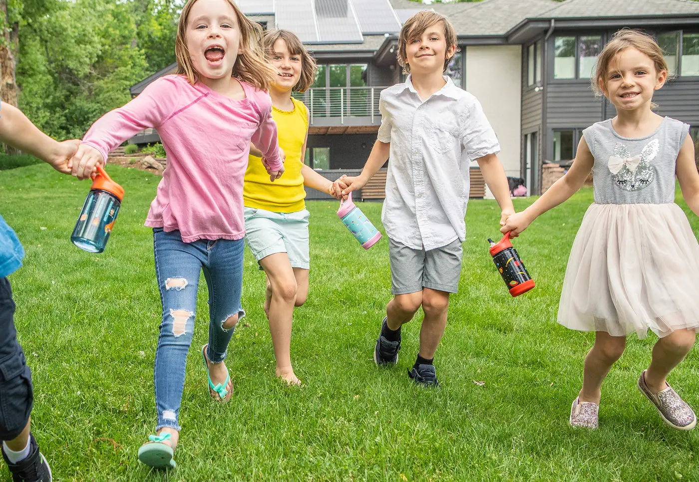 Five children running across a lawn, each with an EcoVessel Splash or Frost kids bottle