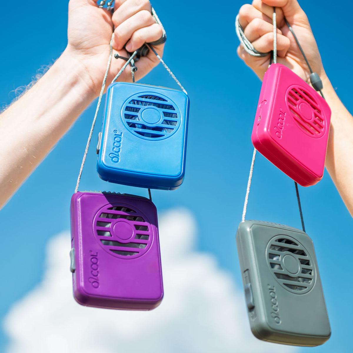 O2COOL necklace fans in four colours held up against a summer sky