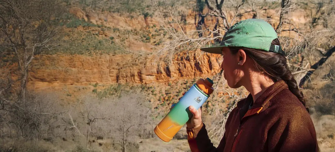 A hiker in a red-rock canyon drinking from her colourful EcoVessel bottle