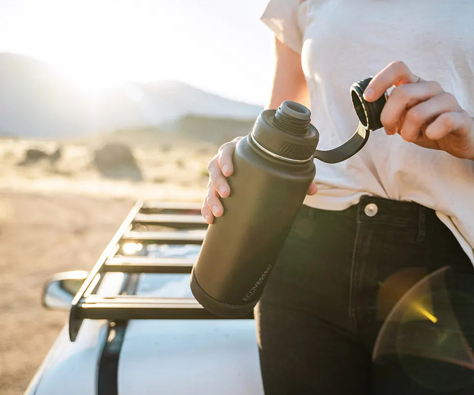 Opening the lid of a black EcoVessel Boulder beside a car roof rack in the evening sun